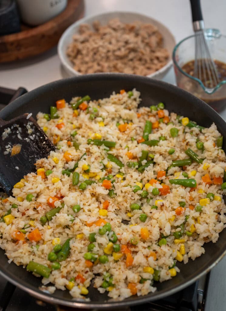 fried rice in a skillet before adding the cooked ground chicken and sauce