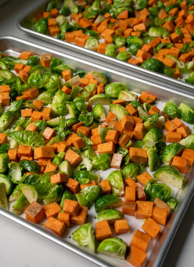 diced sweet potatoes and quartered brussels sprouts on a half sheet pan