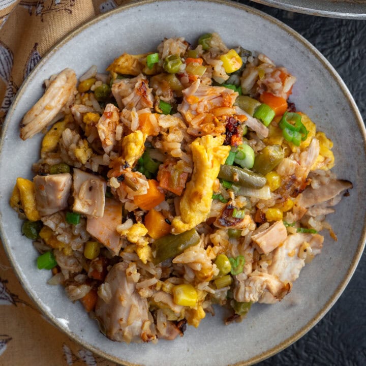 rotisserie chicken fried rice in a bowl with a green onion and chili crisp garnish