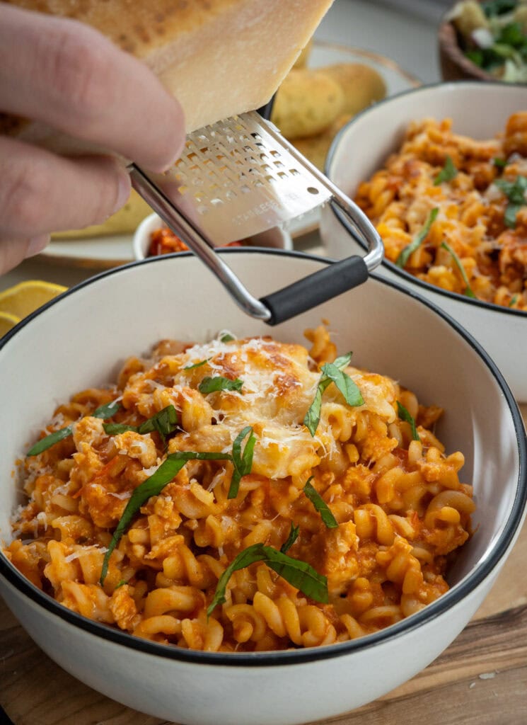 grating parmigiano reggiano over ground chicken pasta