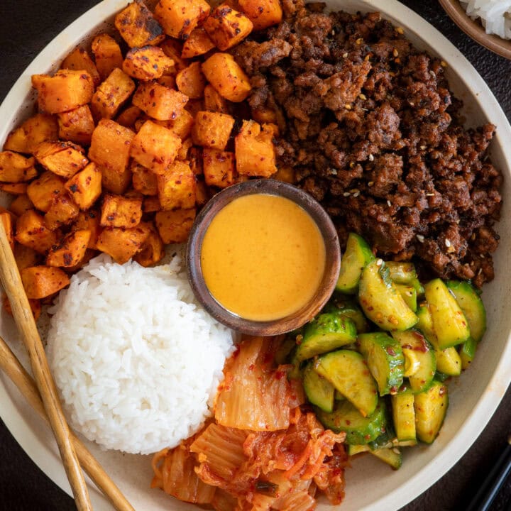 gochujang ground beef in a bowl with roasted sweet potatoes, jasmine rice, kimchi, quick pickled cucumbers, and ssamjang mayo