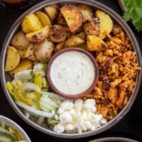 hot honey ground chicken and roasted baby gold potatoes in a bowl with pickle slaw, feta crumbles, and ranch dressing