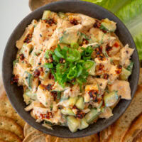 bowl of cottage cheese chicken salad with lettuce wraps, crackers, and toast on a wooden serving platter