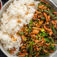 stir fried green beans and ground turkey over rice garnished with chili crisp and sliced green onion
