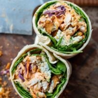 buffalo chicken wrap sliced in half on a cutting board