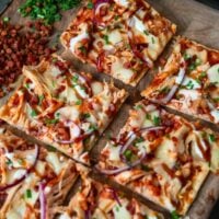 picking up a piece of rotisserie chicken flatbread off a cutting board