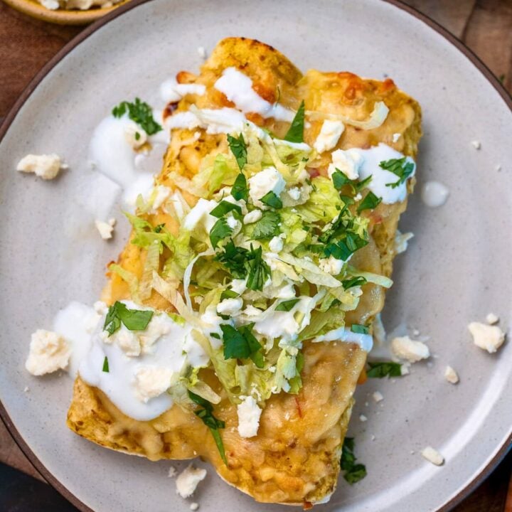 rotisserie chicken enchiladas garnished with queso fresco, cilantro, Greek yogurt, and shredded lettuce