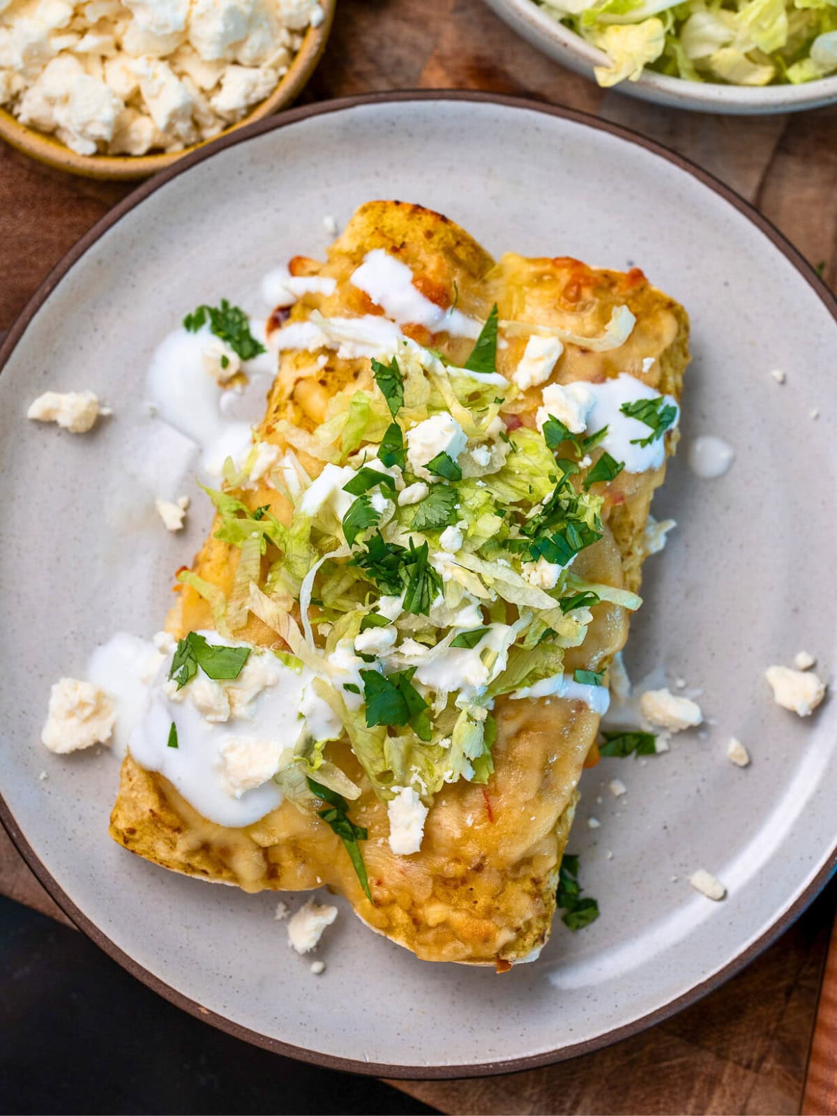 rotisserie chicken enchiladas garnished with queso fresco, cilantro, Greek yogurt, and shredded lettuce