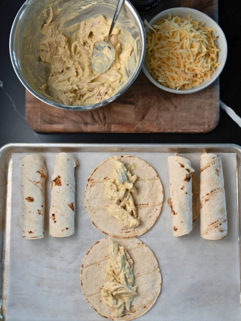 rolling corn tortillas with rotisserie chicken filling