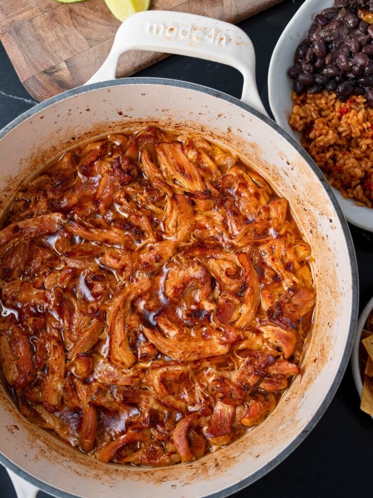 pulled Mexican chicken in a Dutch oven next to a burrito bowl