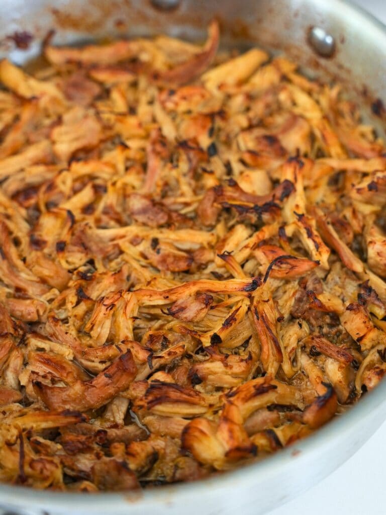 shredded Mexican chicken in a stainless steel sauté pan