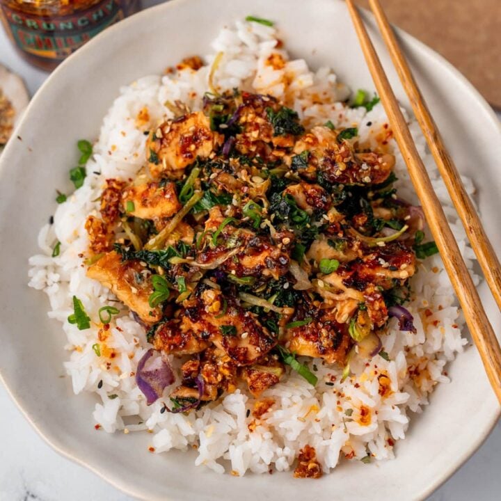 chicken stir fry in a rice bowl with Trader Joe's chili onion crunch and sliced green onion