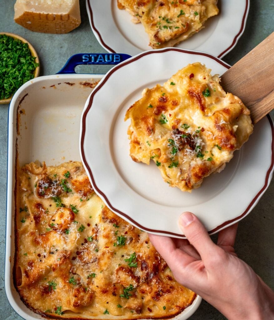serving a slice of lasagna out of a baking dish with a wooden spatula