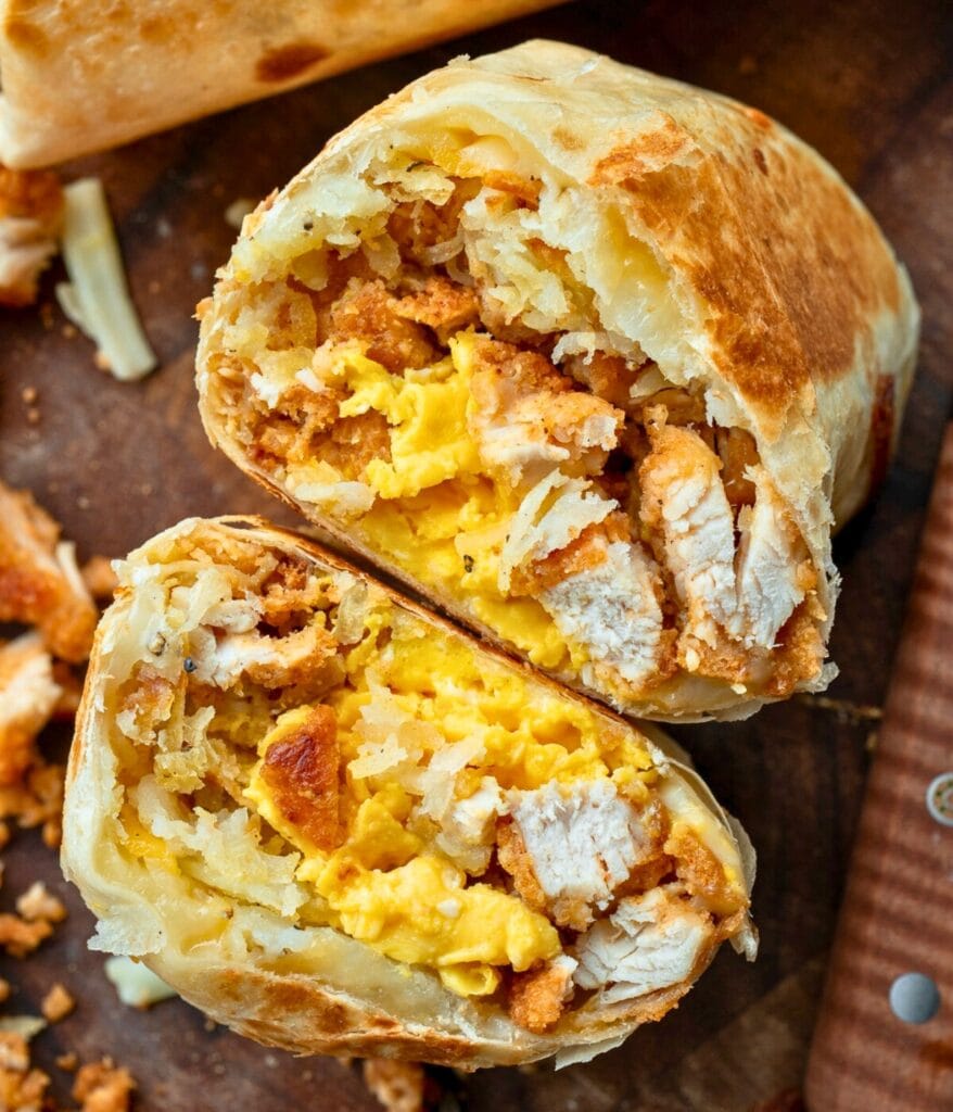chicken breakfast burrito on a cutting board sliced in half