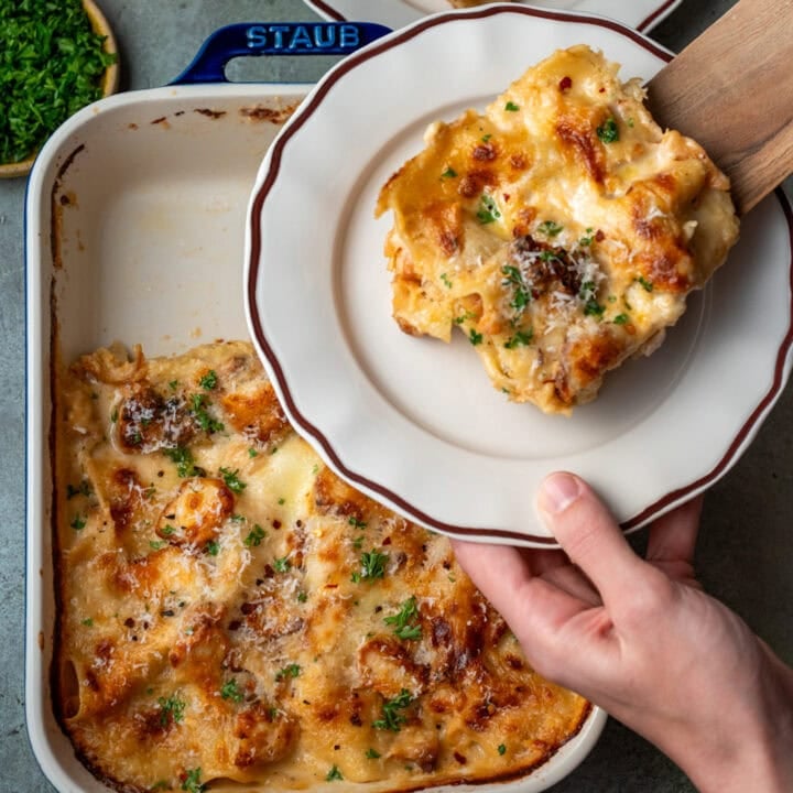 plating a slice of chicken alfredo lasagna with a wooden spatula