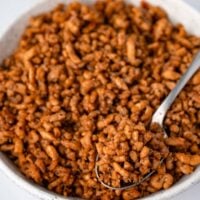 serving breakfast sausage crumbles with a spoon from a white bowl