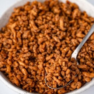 serving breakfast sausage crumbles with a spoon from a white bowl