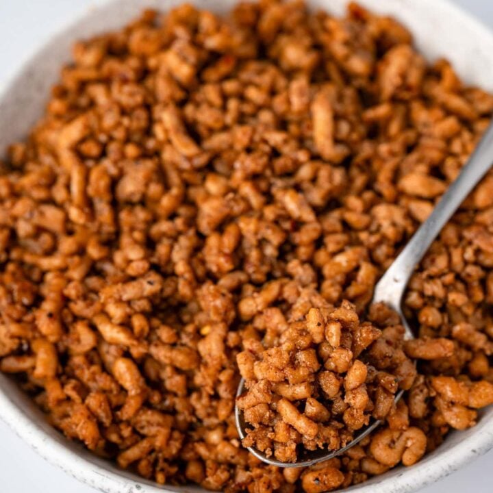 serving breakfast sausage crumbles with a spoon from a white bowl