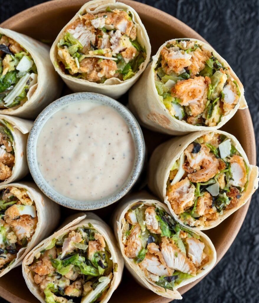 chicken caesar wraps in a bowl with a cup of low calorie caesar dressing
