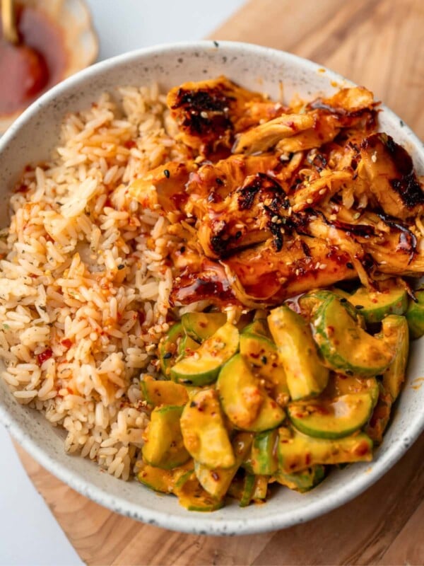 sweet chili rotisserie chicken in a bowl with rice and cucumber crunch salad