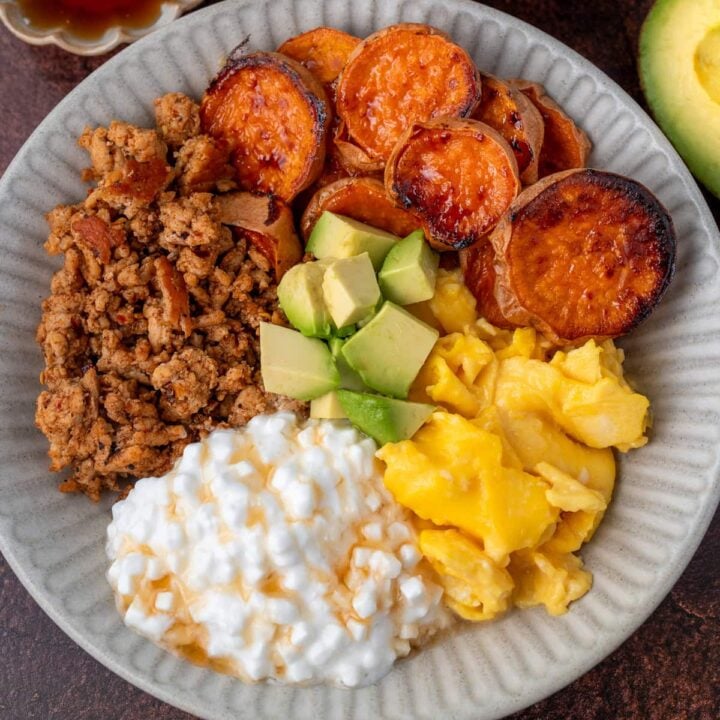 turkey breakfast sausage crumbles, cottage cheese with honey, scrambled eggs, diced avocado, and roasted sweet potatoes in a bowl