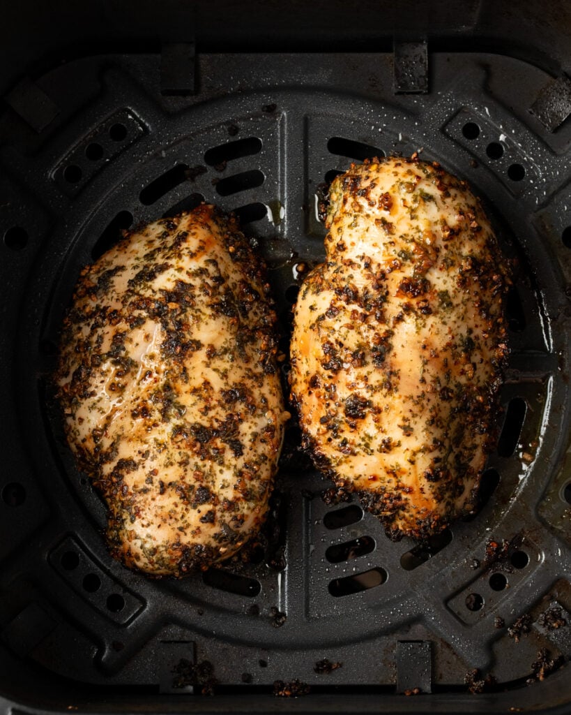two chicken breasts in an air fryer basket after cooking for 15 minutes at 375ºF