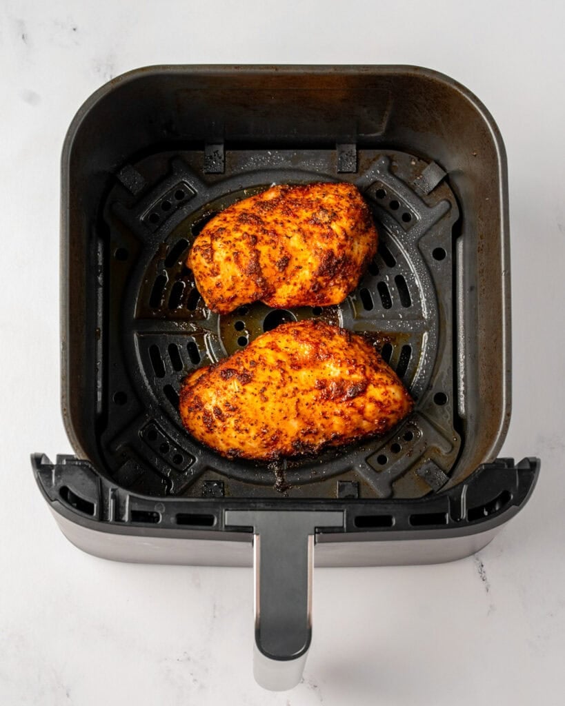 two air fried chicken breasts in a Ninja air fryer basket