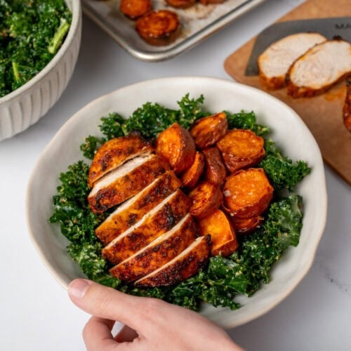 sliced bbq chicken breast in a bowl with kale salad and roasted sweet potatoes
