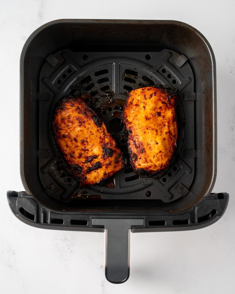 two cooked chicken breasts in a Ninja air fryer pro basket