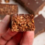 holding a chocolate granola bar with a bite taken out of it