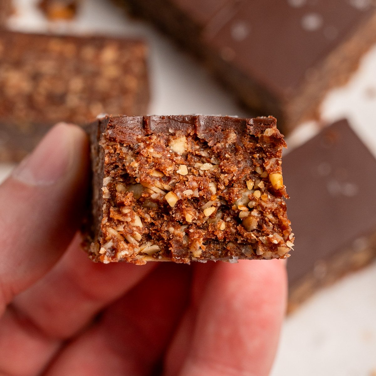 holding a chocolate granola bar with a bite taken out of it