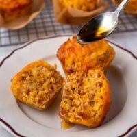 drizzling maple syrup on a halved sausage muffin