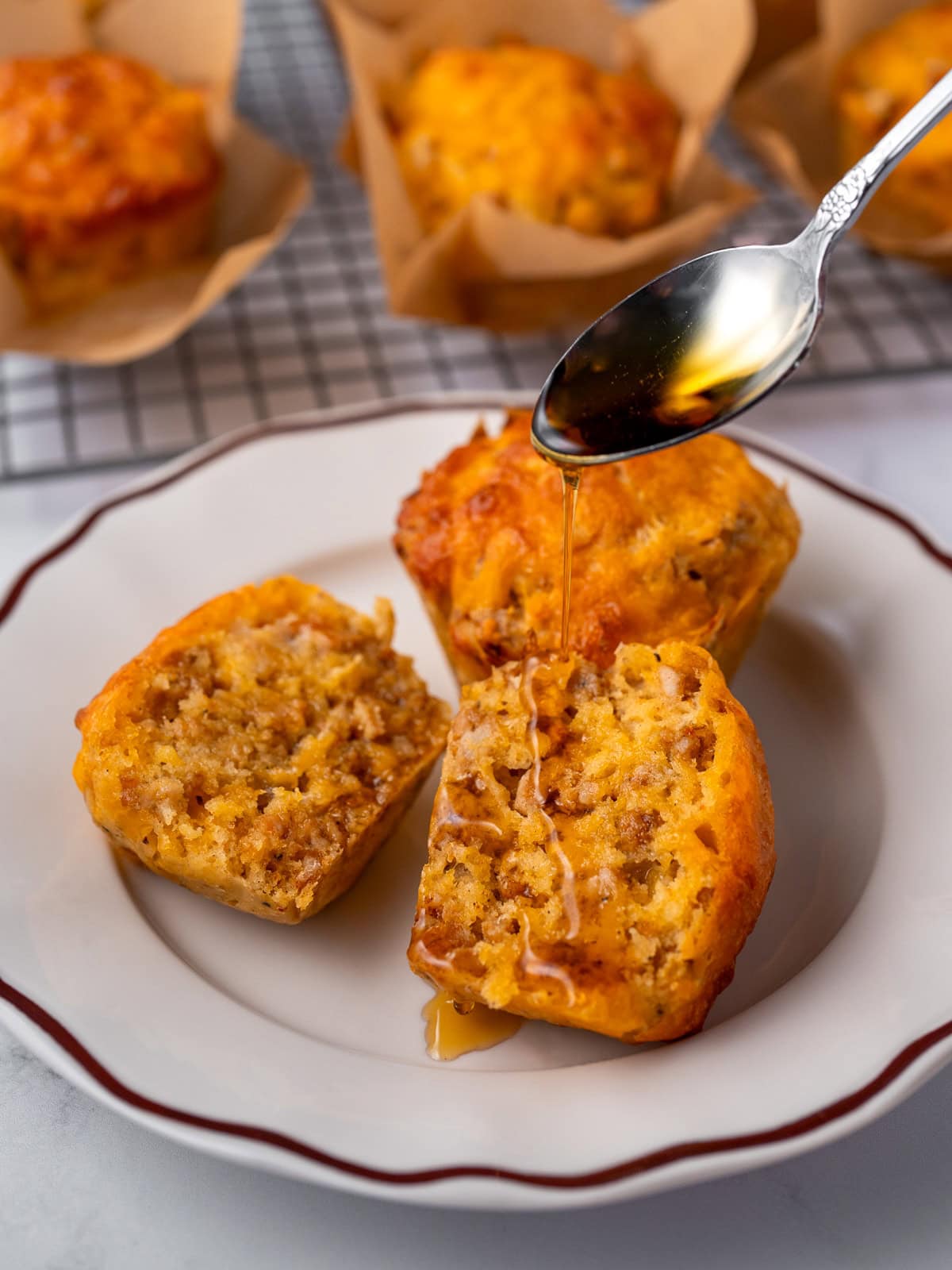 drizzling maple syrup on a halved sausage muffin