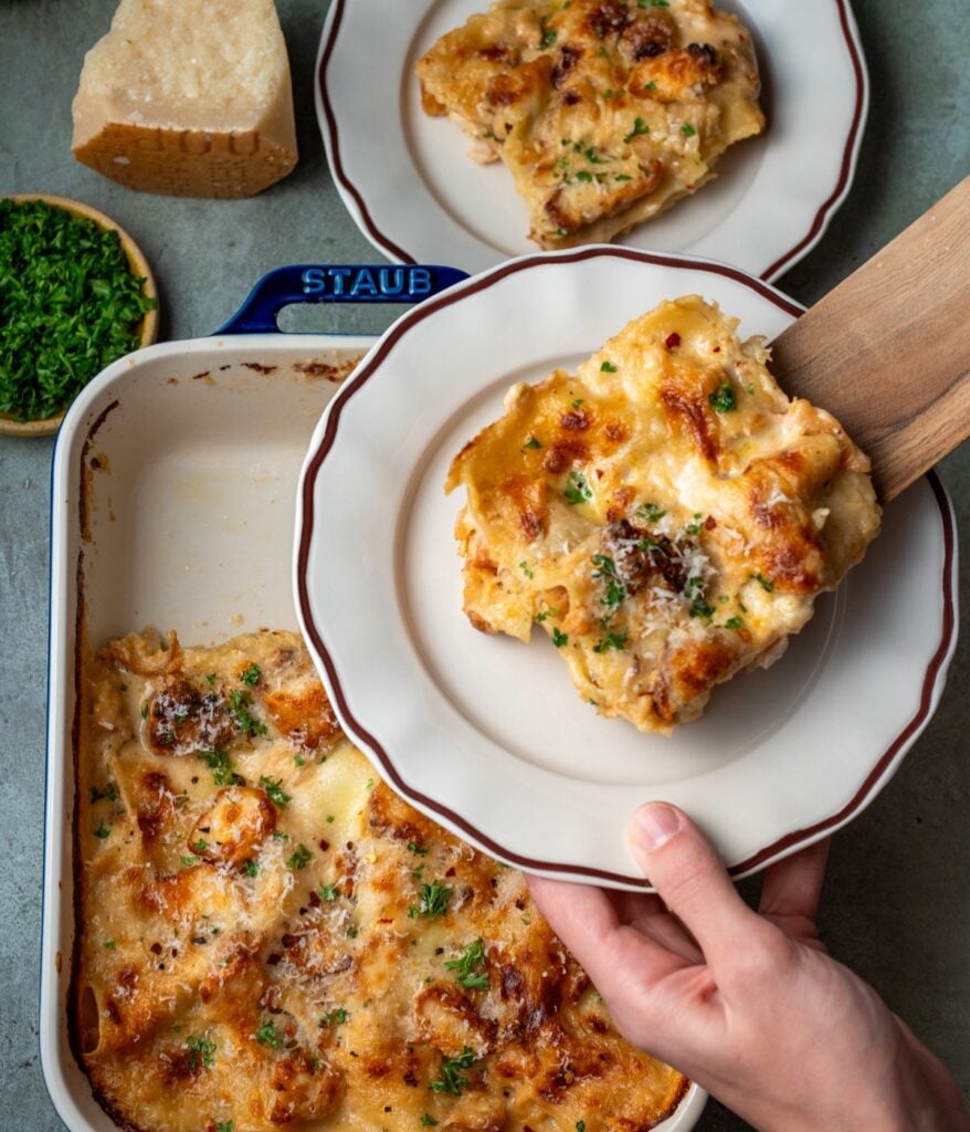 serving alfredo lasagna with a wooden spatula