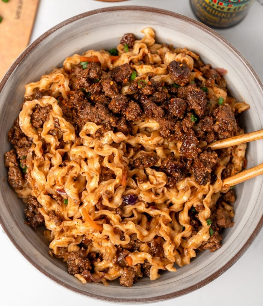 chopsticks in a bowl of crispy beef noodles