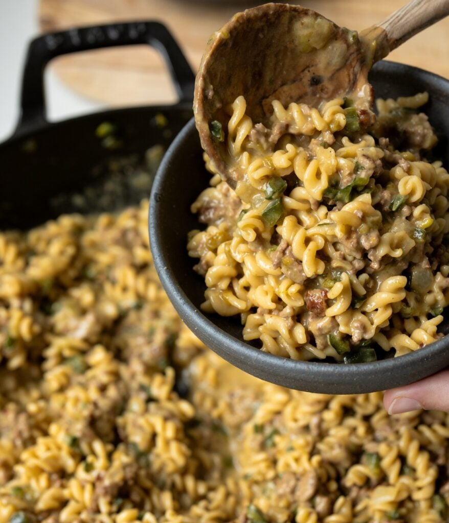 serving beefy mac and cheese made with Goodles from a skillet with a wooden spoon