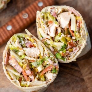 Italian grinder wrap sliced in half on a cutting board