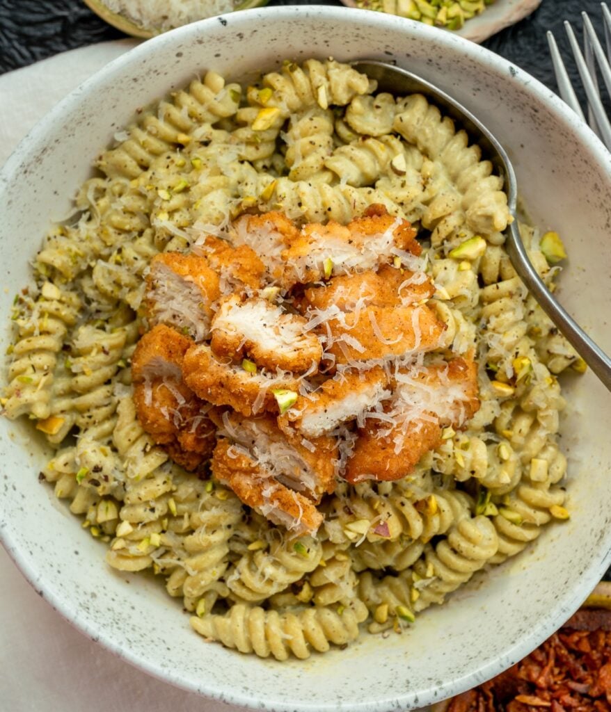 chopped lightly breaded chicken on a bowl of cottage cheese pesto pasta