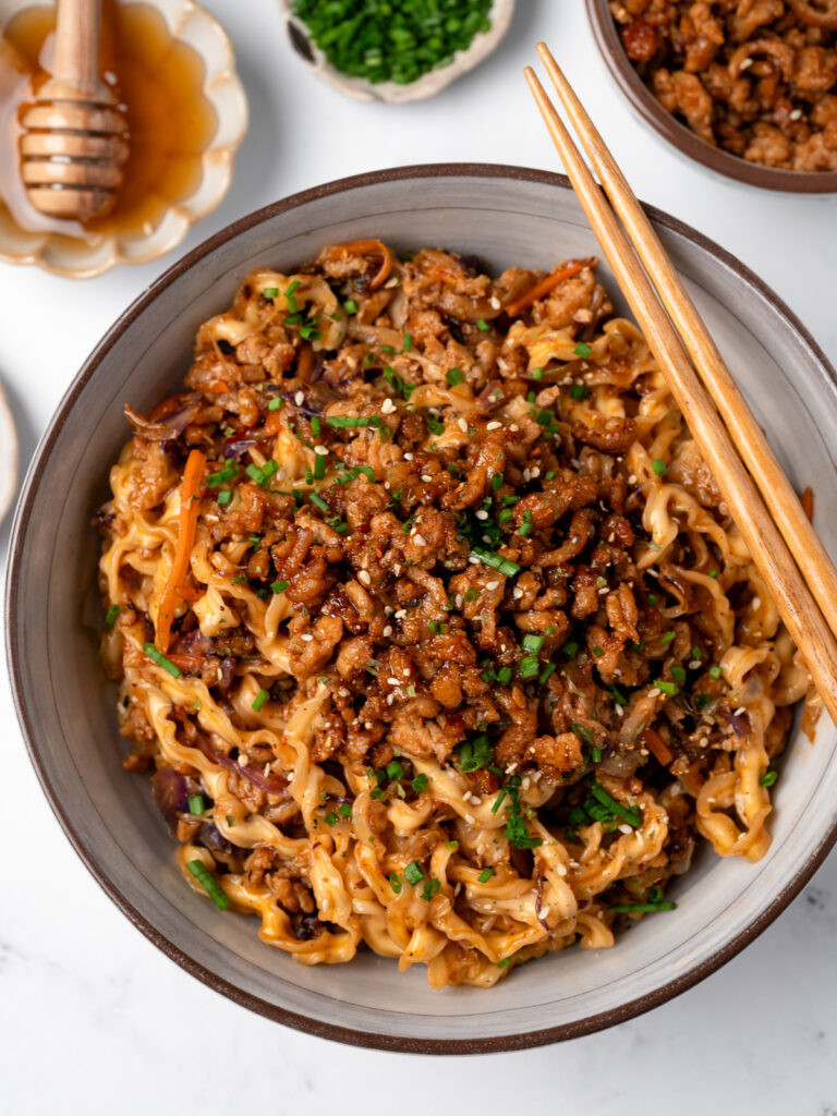crispy ground chicken crumbles on top of a bowl of noodles 