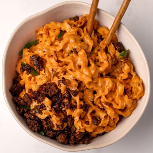 creamy gochujang knife cut noodles in a bowl with crispy sesame ground beef and chopsticks