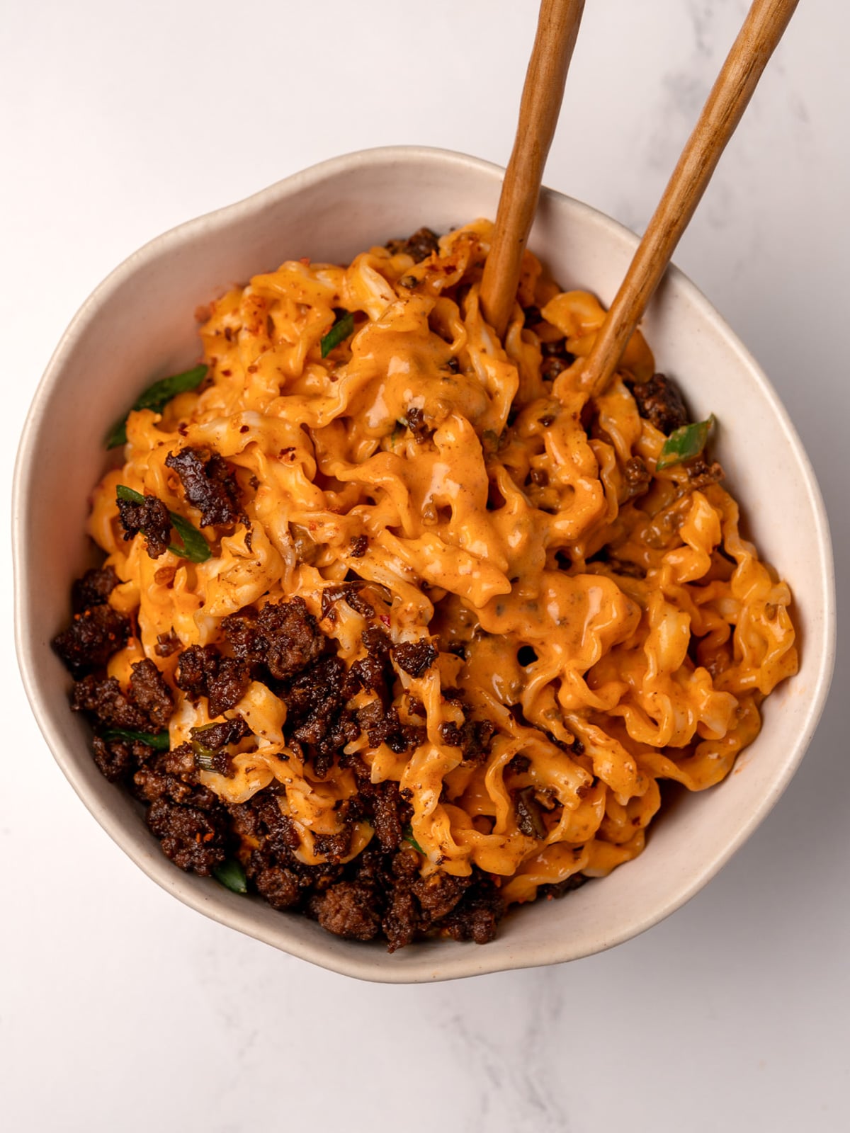 creamy gochujang knife cut noodles in a bowl with crispy sesame ground beef and chopsticks