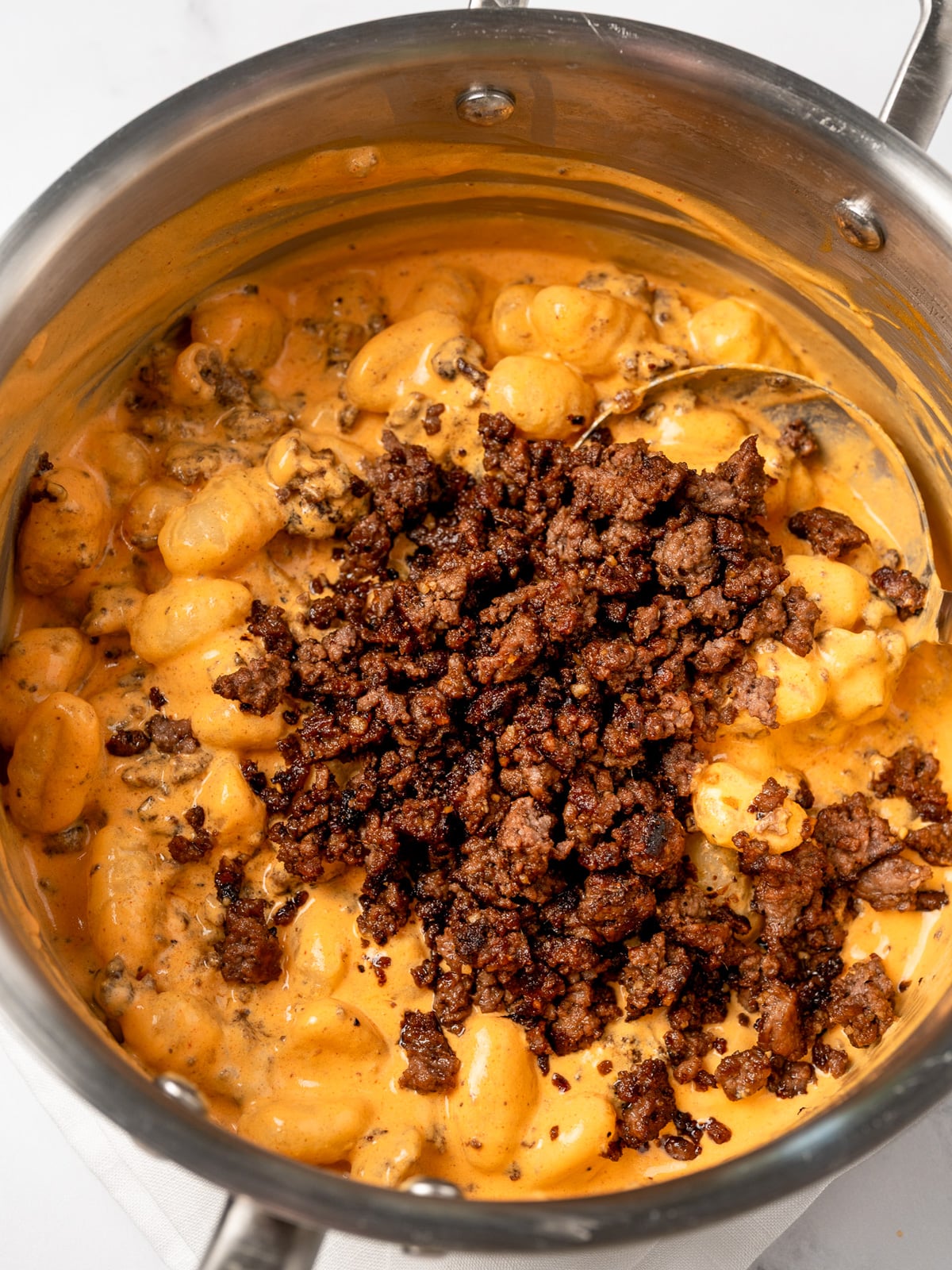 mixing sesame garlic ground beef into gochujang gnocchi