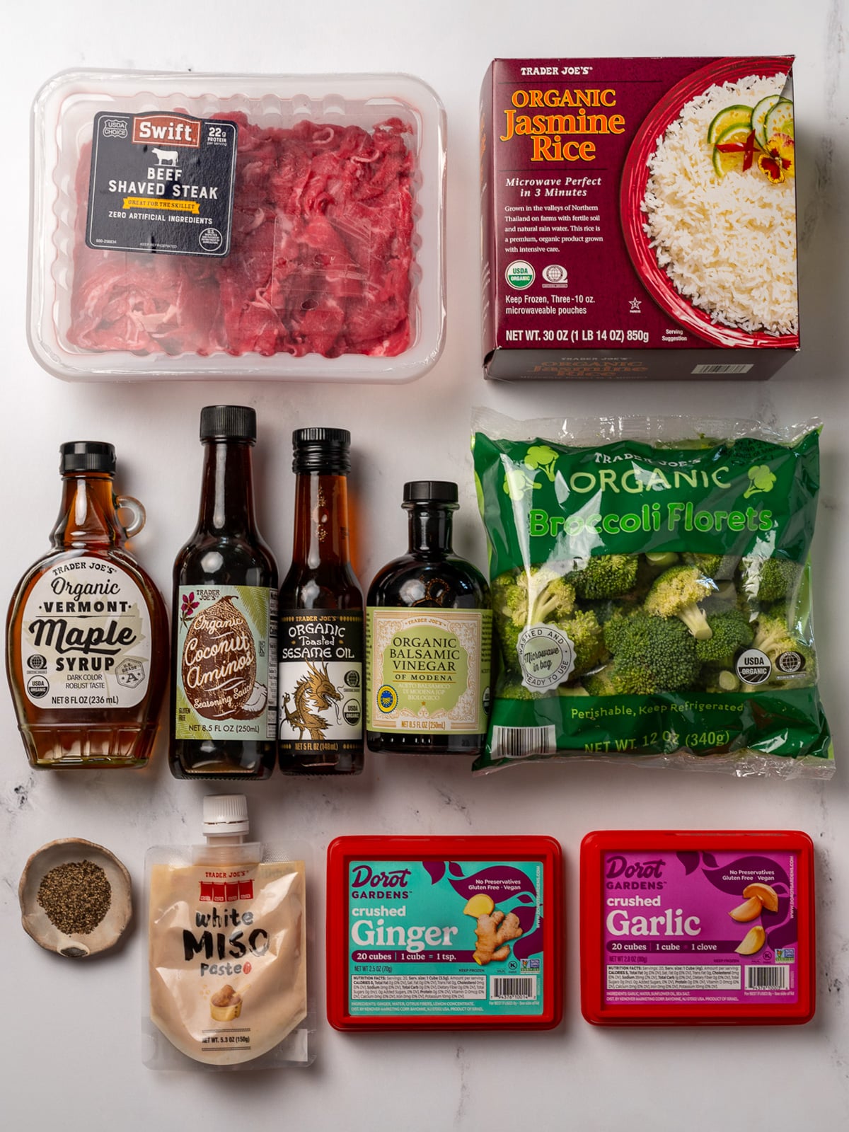 Trader Joe's beef shaved steak, steamed jasmine rice, maple syrup, toasted sesame oil, coconut aminos, balsamic vinegar, broccoli florets, black pepper, white miso paste, and frozen cubes of garlic and ginger
