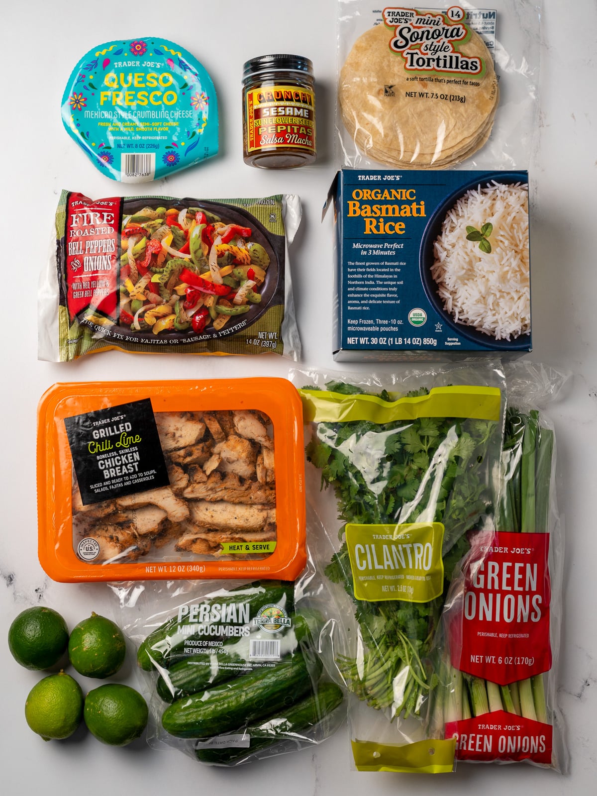 Trader Joe's queso fresco, salsa macha, tortillas, frozen peppers and onions, frozen basmati rice, grilled chili lime chicken breast, limes, cucumbers, cilantro, and green onions