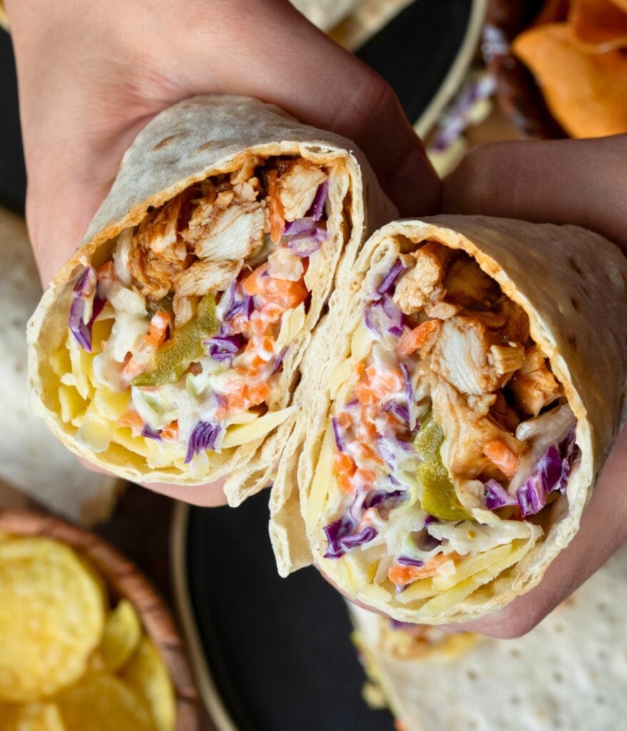 holding a halved bbq chicken wrap