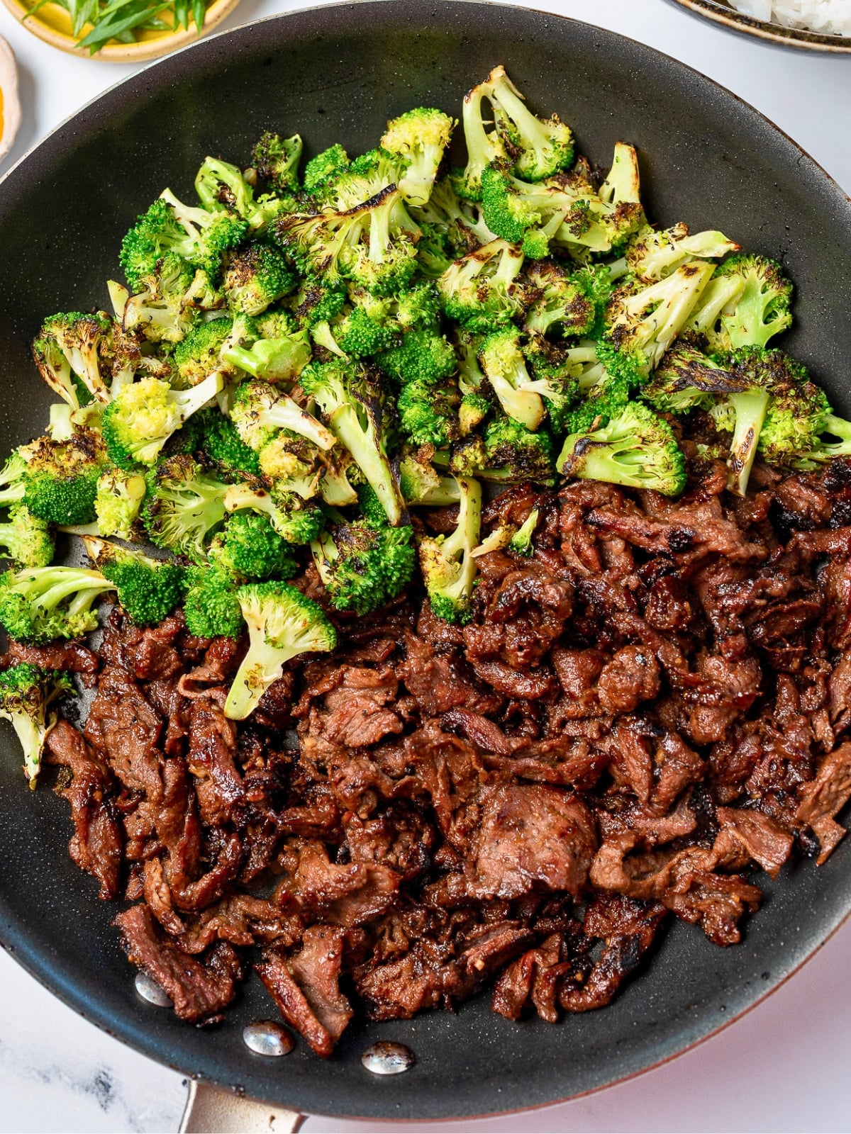 prepared black pepper beef in a pan with pan roasted broccoli on the other side
