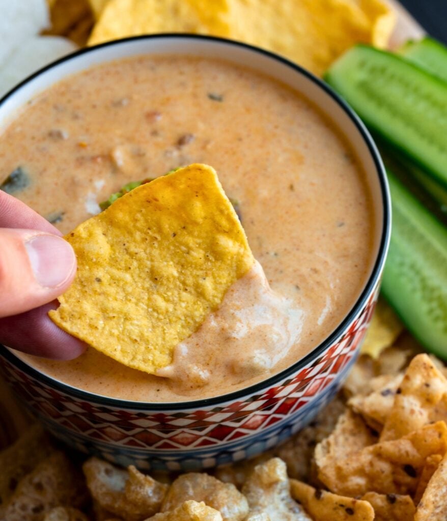 dipping a tortilla chip in queso