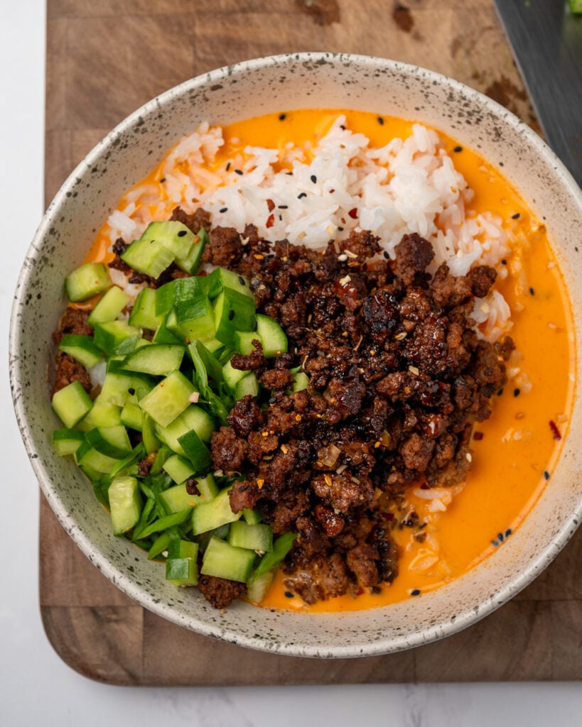 caramelized ground beef, diced cucumber, and sliced green onion served over jasmine rice in a bowl of creamy gochujang broth