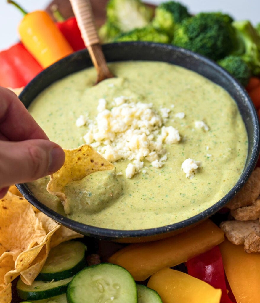 dipping a baked scoop tortilla chip in a bowl of cottage cheese dip