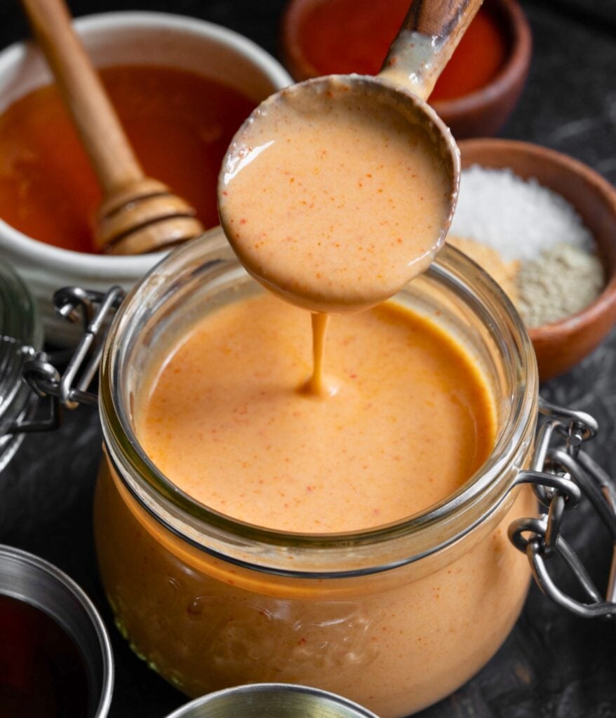 a wooden spoon dipped in a jar of yum yum sauce